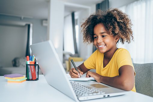 Young student watching lesson online and studying from home. Girl using laptop for online lessons. Homeschooling and distance learning concept.